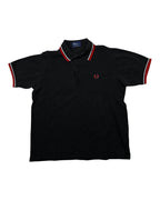 Casual Circuit. Black men's cotton polo shirt with red and white contrast stripes on the collar and sleeves, Fred Perry logo.